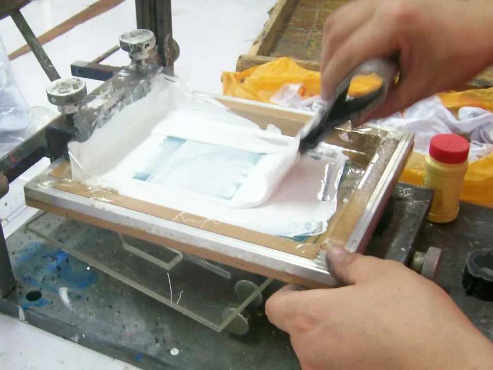 Archived manufacturing photograph of an operator screen printing a base layer on a plastic part