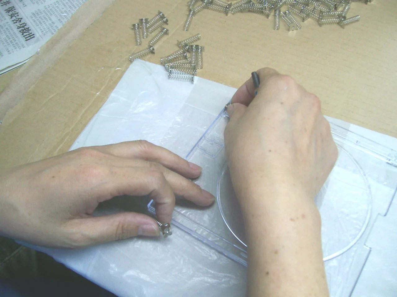 Operator positioning a metal spring in the locating slot of a clear plastic housing