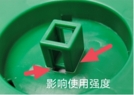Pink arrows point to damaged and whitened areas at the base of a raised green plastic feature, labelled as reducing strength in use.